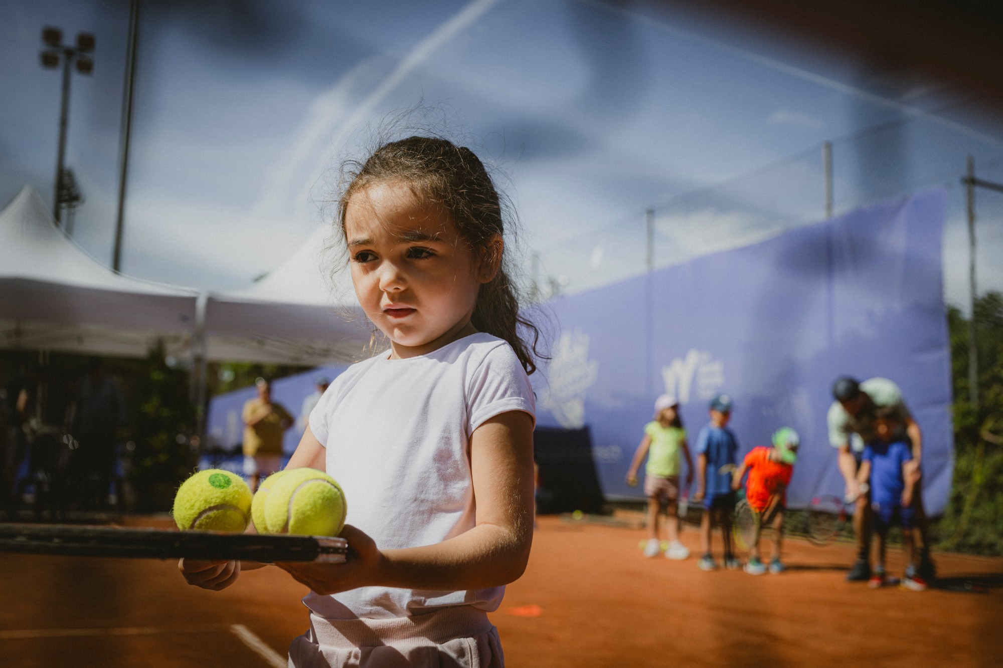 Une jeune joueuse tient une raquette et des balles de tennis